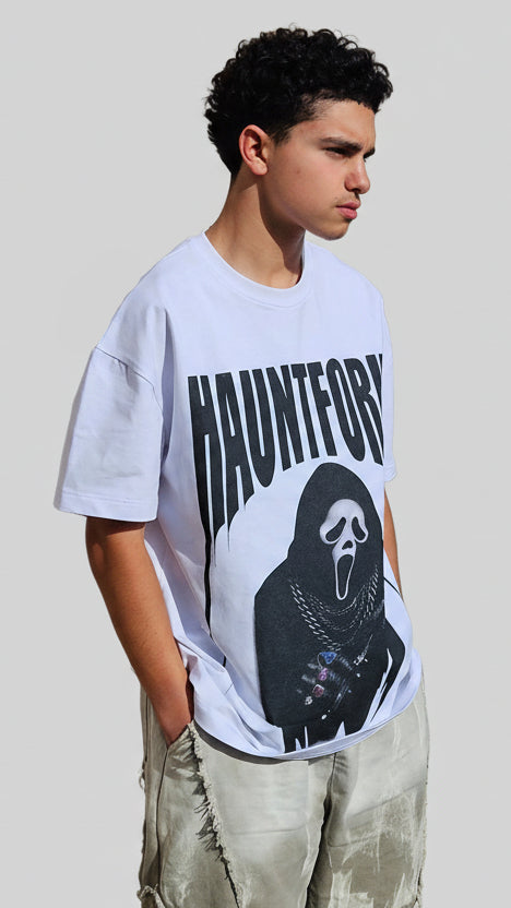 Person lying on a tiled floor wearing a white t-shirt with black text and graphics.